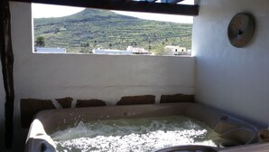 A hot tub with a view of a mountain and buildings. - "TRIGO" quaint studio apartment in an old mill from the year 1912. (Maguez)