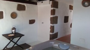 A spa area with a hot tub, a small table with a lantern, and a rustic wall design. - "TRIGO" quaint studio apartment in an old mill from the year 1912. (Maguez)