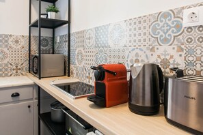 Et køkken med bordplade, brødrister, kaffemaskine og elkedel.