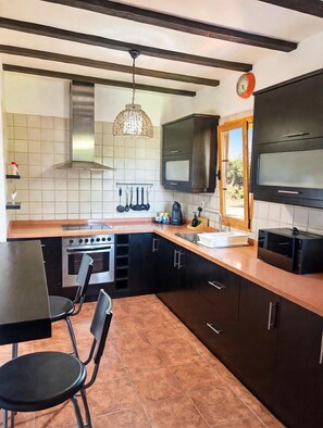Una cocina moderna con estufa, horno y comedor con sillas.