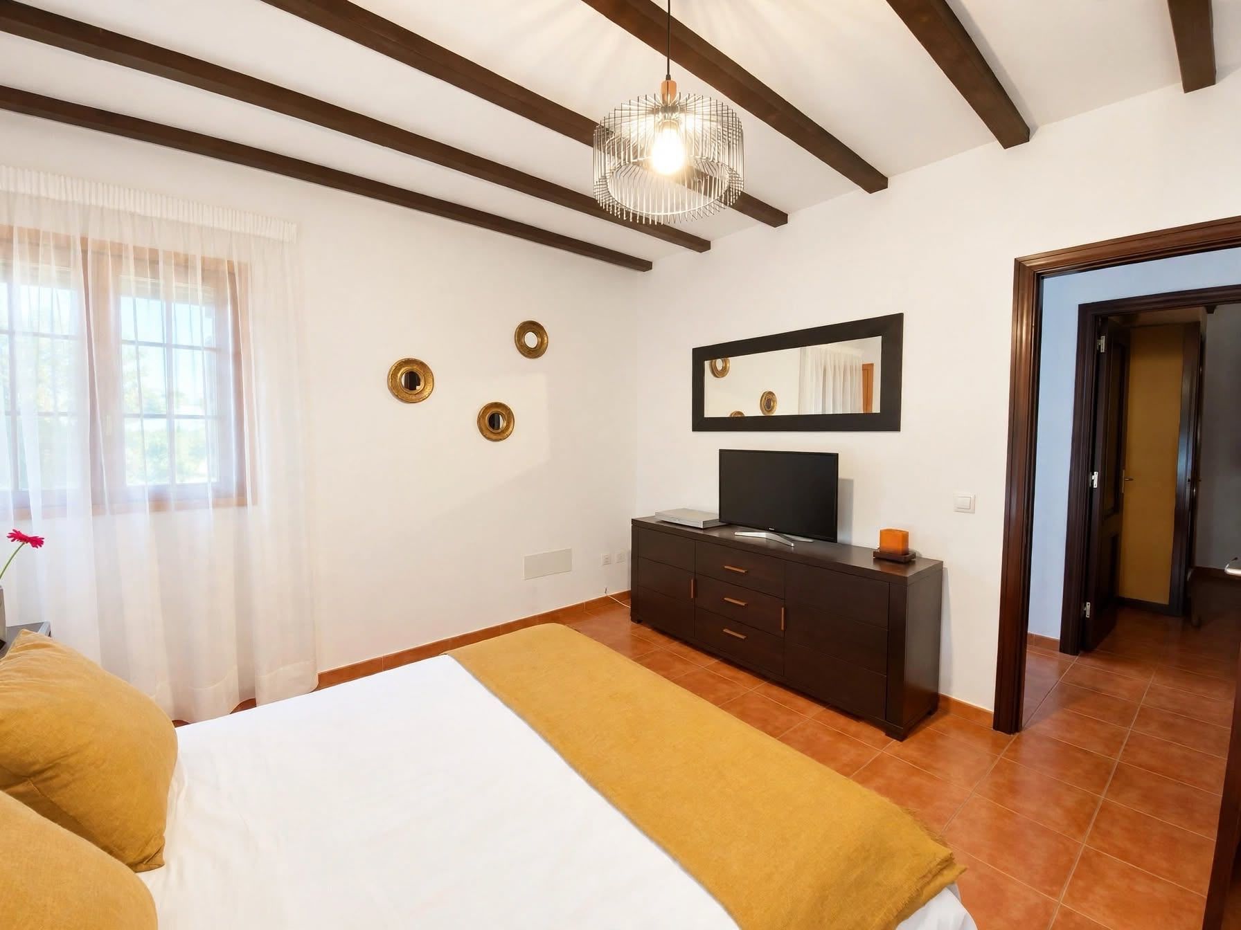 Un dormitorio con cama, cómoda, televisor y espejo.