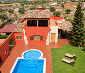 Una casa con piscina, patio cubierto y césped.