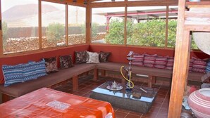A covered outdoor seating area with a wooden bench, cushions, and a hookah. - Villa Nido Cari—Fuerteventura Rural Oasis (Casillas de Morales)
