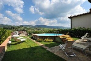 A backyard with a swimming pool, lounge chairs, and a stone patio. - Private villa with pool in Greve in Chianti- Casa Amaranta (Greve in Chianti)