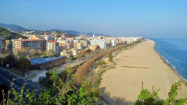 Een kuststadsgezicht met een zandstrand, een boulevard met gebouwen en een helder uitzicht op zee.