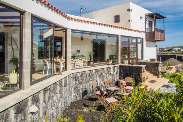 A modern house with large windows, a balcony, and a stone wall. - Light & Spacious House in the Vineyard region, just in the middle of the island (Masdache ( Tías))