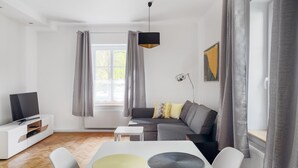 Een moderne woonkamer met een bank, een televisie en een eettafel met placemats.