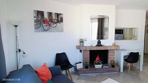 Un salon avec une cheminée, un canapé, une table à manger et un miroir.