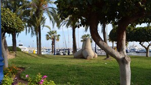 Un parc avec de l’herbe, des arbres et une grande sculpture en pierre.