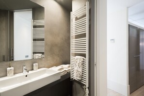 Un baño moderno con un lavamanos grande, un espejo y un perchero para toallas.