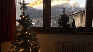 Ein Weihnachtsbaum mit Lichtern und einem Sternenornament vor einem Fenster mit Blick auf ein Gebirge.