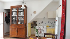 A dining area with a wooden cabinet, a table with a white tablecloth, and a vase with flowers. - Casa del Vento in San Cono, ancient stone dwelling among olive trees (Polizzi Generosa)