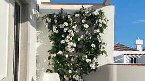 A balcony with a white sofa, a potted plant with white flowers, and a pergola structure. - The White House - Tavira Historic old town center (Tavira)