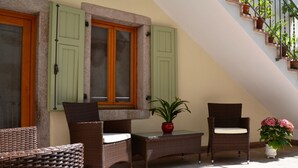 Ein Balkon mit Korbmöbeln, einer Topfpflanze und einer Treppe mit Blumentöpfen.