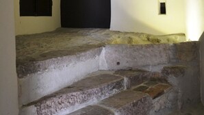 Eine Steintreppe führt zu einer dunklen Tür, oberhalb der Tür befindet sich ein kleines Fenster.
