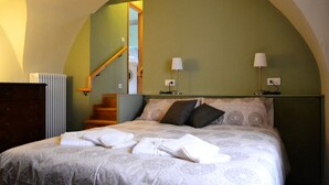 Ein Schlafzimmer mit einem Bett, zwei Nachttischlampen, einer Kommode und einer Treppe zu einem anderen Raum.