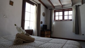 A bedroom with a bed, a window, a desk, and a potted plant. - " MILLO" characteristic studio apartment in an old motor mill from the year 1912. (Maguez)