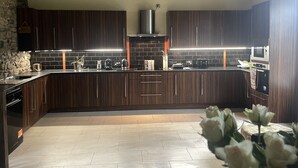 Una cocina moderna con armarios de madera oscura, encimera negra y pared de piedra.
