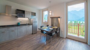 Et moderne køkken med spiseplads, et stort vindue med udsigt til et bjerglandskab og en balkon.