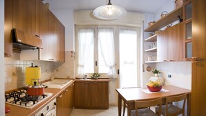 Une cuisine avec des meubles de rangement en bois, une cuisinière à gaz, un évier et une table à manger avec des chaises.