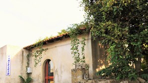 Un edificio con pared de piedra, techo de tejas y una puerta con un letrero encima.