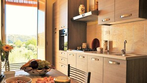 Una cocina moderna con vistas al exterior, que incluye una mesa de comedor preparada con comida, un bol de fruta y un jarrón con flores.