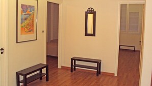 Un couloir doté d’un plancher en bois, d’un tableau encadré, d’un miroir et d’un banc.