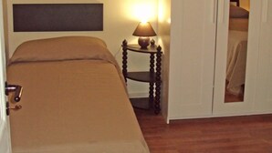Une chambre à coucher avec un lit, une table de chevet avec une lampe, une armoire et un tableau accroché au mur.