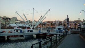 Un port de plaisance situé au bord de l’eau, avec des bateaux amarrés, une grande grue blanche et des bâtiments en arrière-plan.