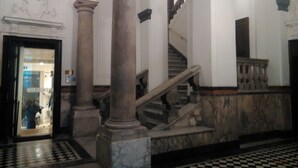 Un magnifique escalier, orné de colonnes de marbre et doté d’un sol à carreaux, mène à un niveau supérieur.