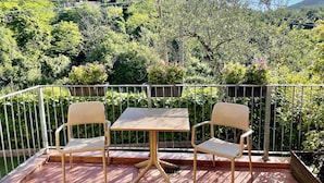 Eine Terrasse mit zwei Stühlen und einem Tisch, umgeben von einem Metallgeländer.