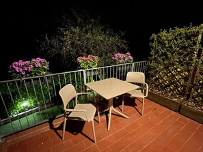 A terrace with a table and two chairs, surrounded by a metal railing. - new garden apartment (lerici)