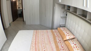 Ein Schlafzimmer mit Bett, Kleiderschrank und angrenzendem Badezimmer.