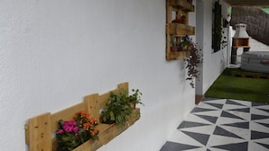 A hallway with a white wall, wooden shelves with plants, a thatched roof, and a checkered floor. - Disconnect from the routine and enjoy the countryside (Berja)