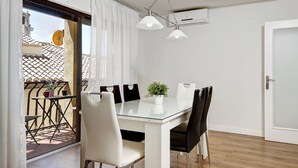 Un espace repas moderne avec une table en verre, des chaises blanches et un luminaire suspendu.