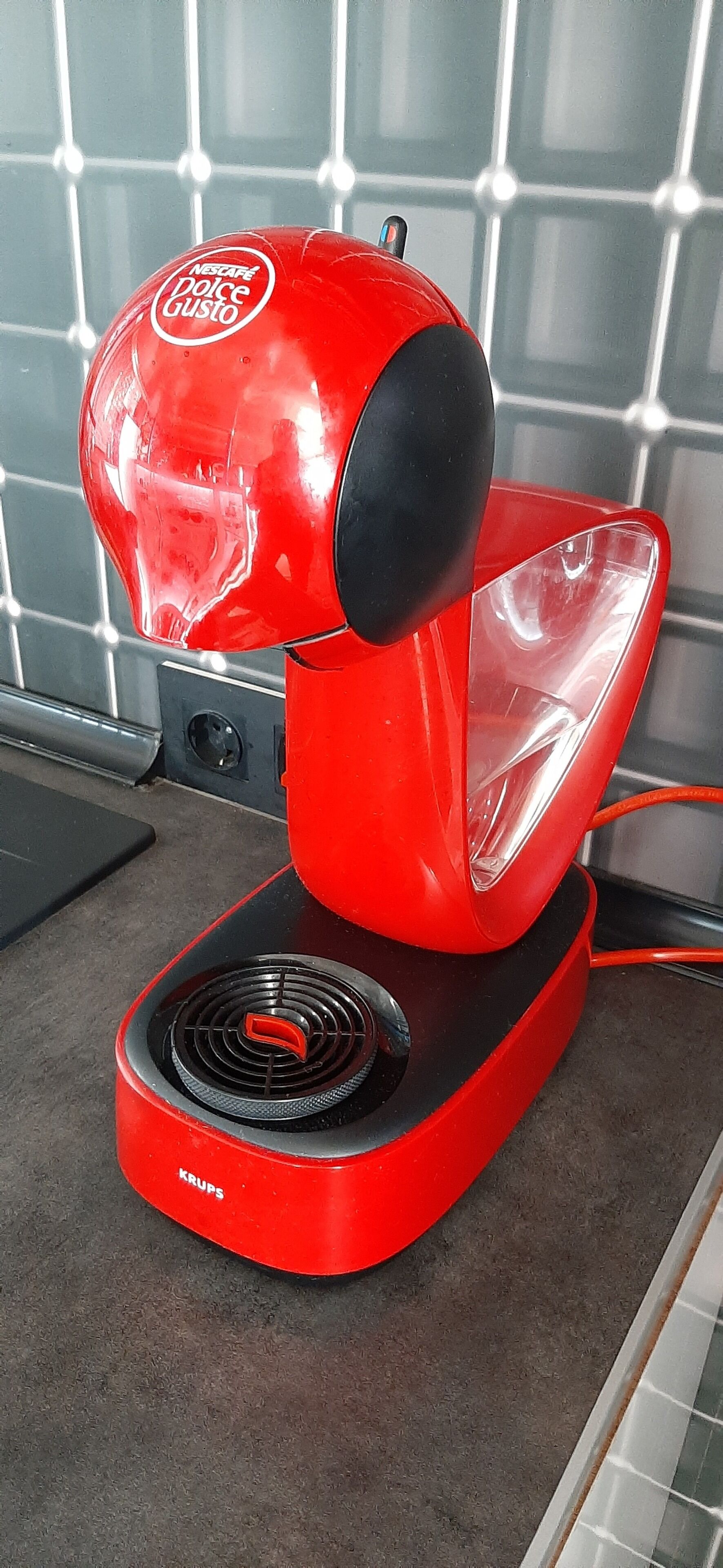 Una cafetera roja Nespresso Dolce Gusto sobre la encimera de la cocina.