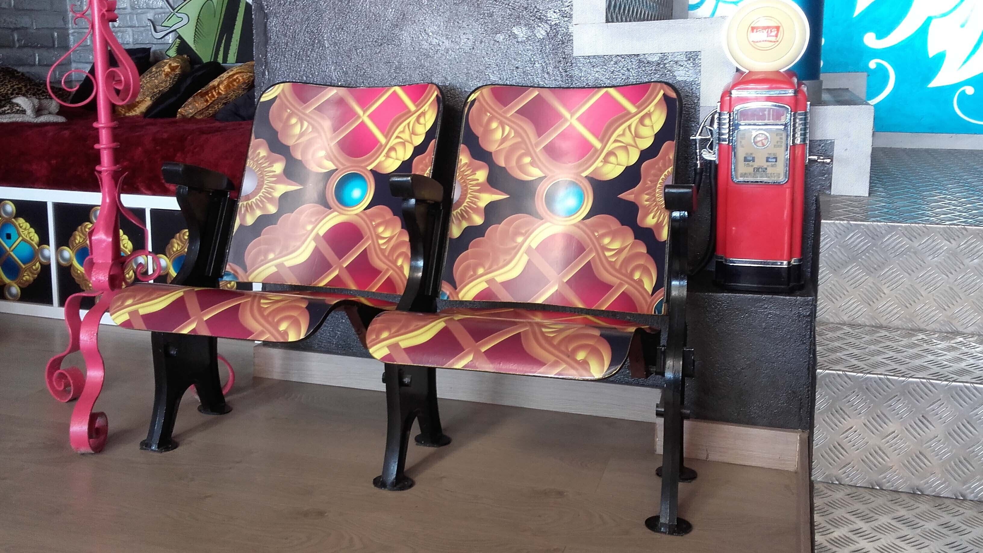 En bænk med detaljeret ryg og en rød telefonkiosk.