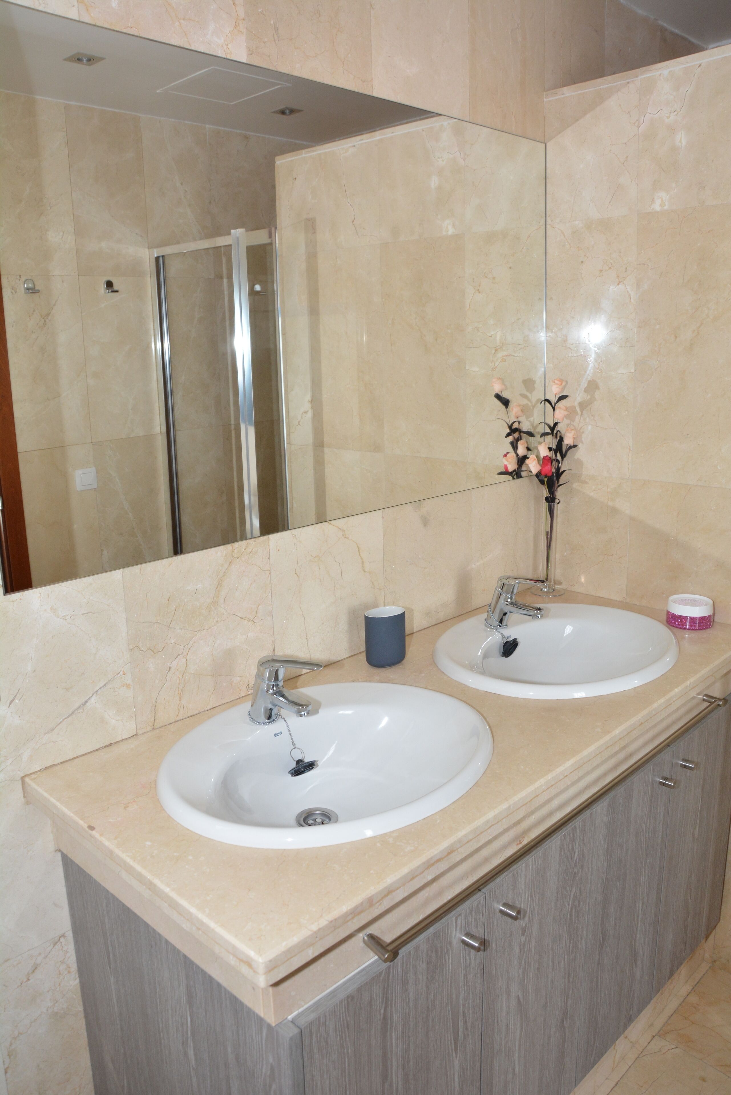 Casa de banho com duas pias, um espelho e chuveiro.