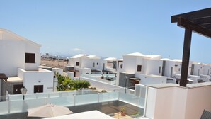 A rooftop terrace with white buildings, a glass balustrade, and a clear view of the beach. - Beautiful and luxurious villa with heated pool and free Wi-Fi in Playa Blanca.  (Yaiza)