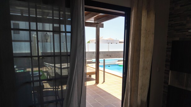 A room with a sliding glass door leading to an outdoor area with a pool and a patio. - Beautiful and luxurious villa with heated pool and free Wi-Fi in Playa Blanca.  (Yaiza)