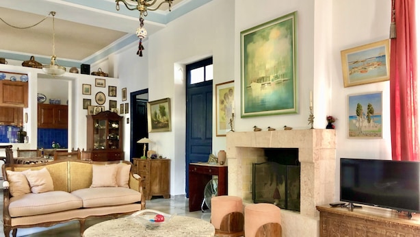 A spacious living room with a sofa, a coffee table, a fireplace, and a television. - Traditional Villa Aegina Port (Aigina)