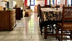 A dining room with a hexagonal tiled floor, a chandelier, and a dining table with floral tablecloths. - Traditional Villa Aegina Port (Aigina)