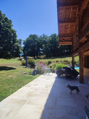 A patio area with stone flooring, outdoor furniture, and a dog. - COSY STUDIO IN A LARGE CHALET IN THE COUNTRYSIDE, fully renovated (Brié-Et-Angonnes)