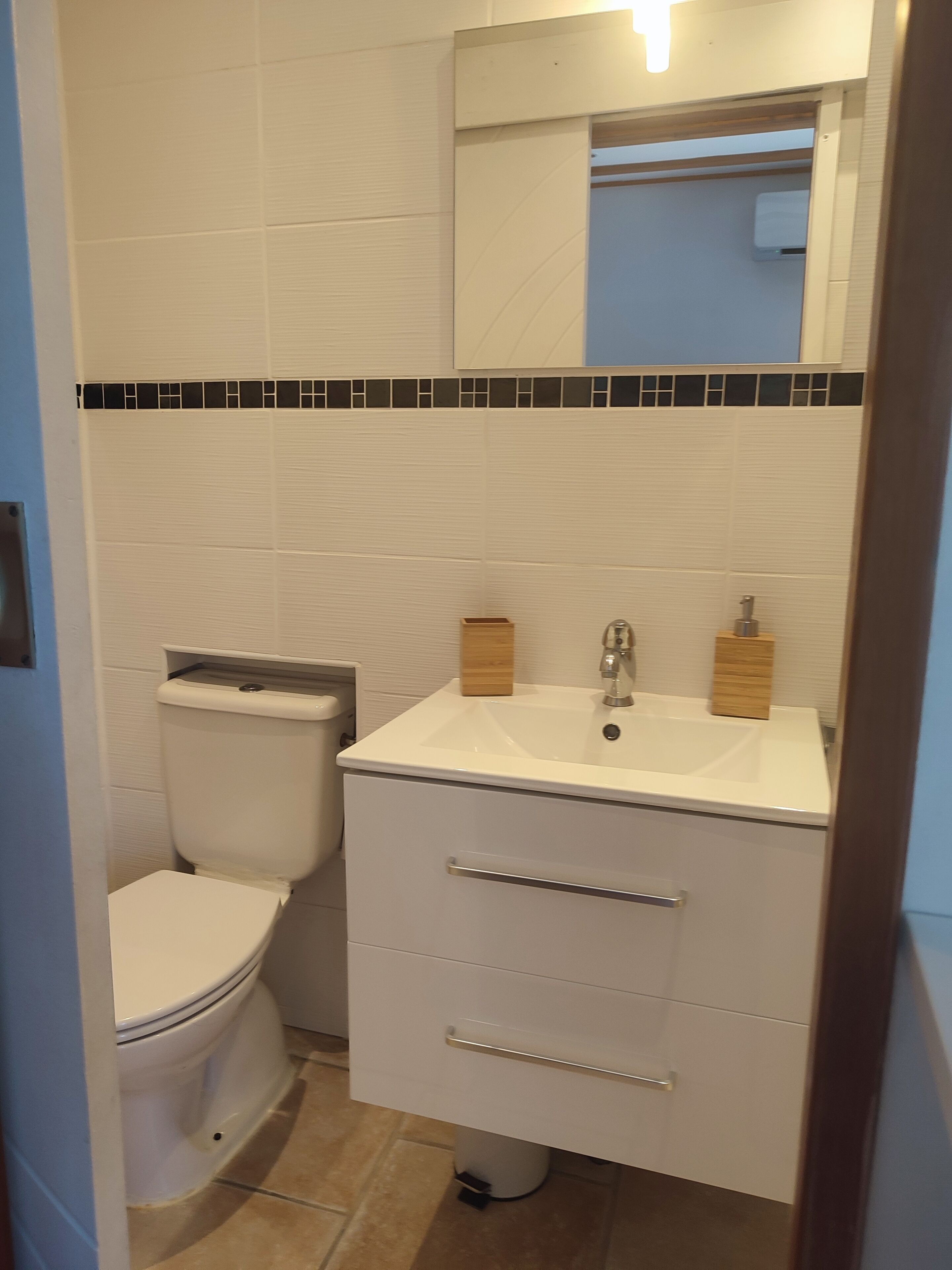 A bathroom with a toilet, sink, and mirror.