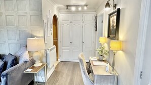 En kompakt opholdsstue med sofa, spisebord med stole, en radiator og en lille måtte.