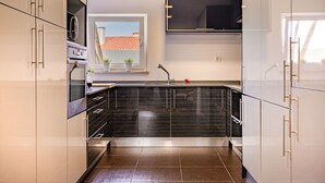 A modern kitchen with a built-in oven, a microwave, and a window above the sink.