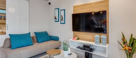 A modern living room with a sofa, coffee table, TV, and decorative items.