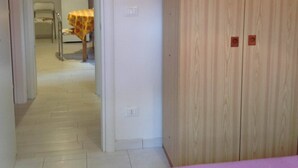 A room with a wooden wardrobe, a dining table with a yellow tablecloth, and a chair.