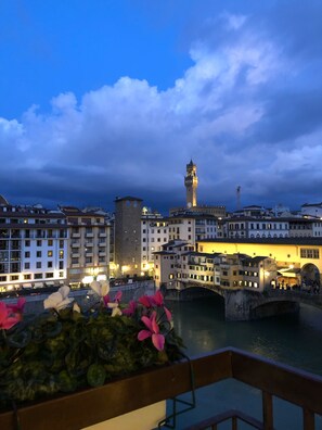 A riverside cityscape with historic buildings, a prominent clock tower, and a bridge.