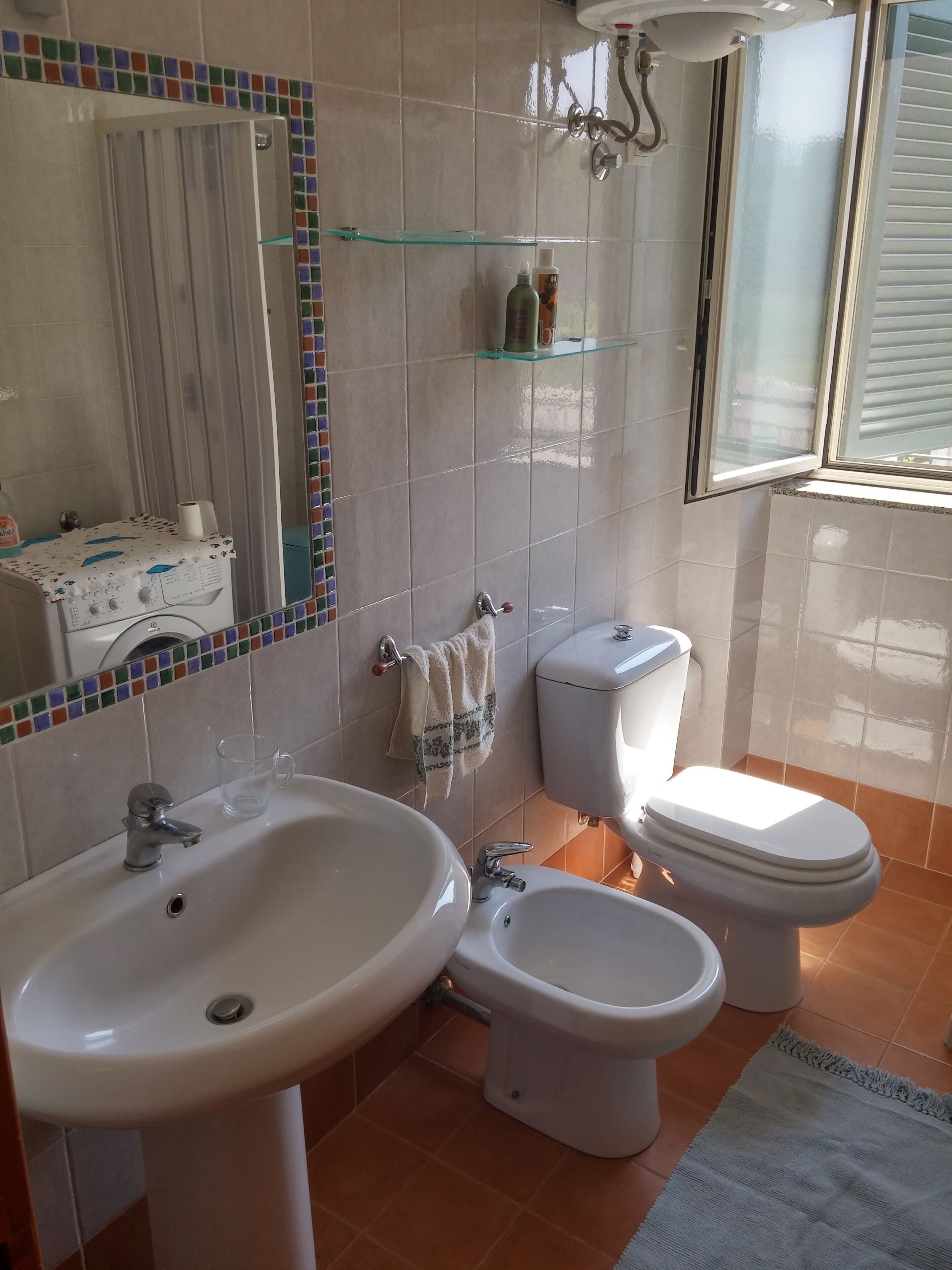 A bathroom with a sink, bidet, toilet, and a mirror.